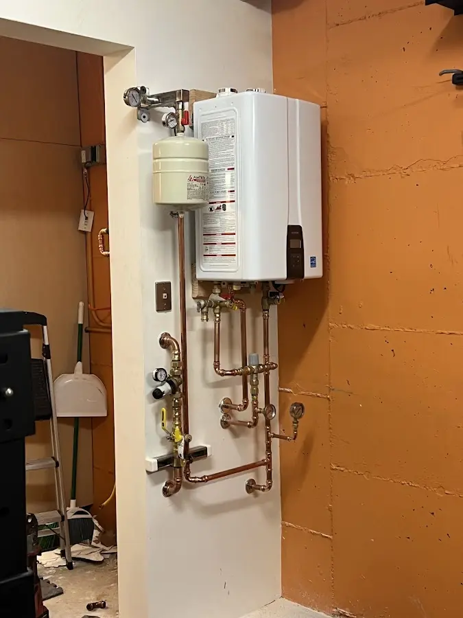 Plumbing technician inspecting water heater connections in Dent